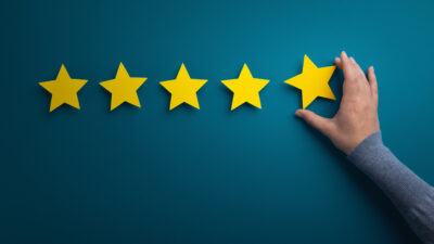 5 etoiles sur fond coloré avec une main qui saisie une étoile